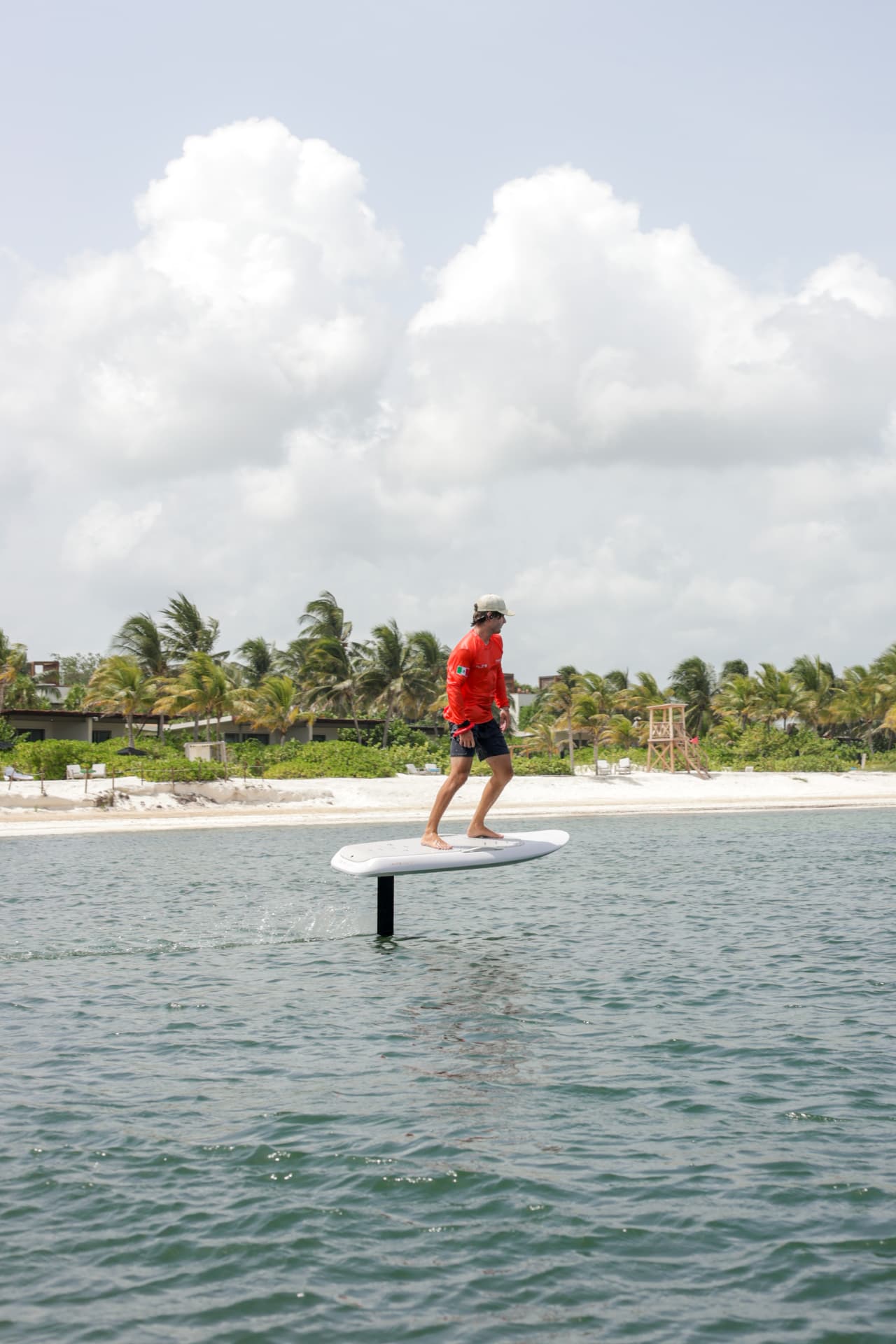 Rider flying a Fliteboard past the white sand beach at Mayakoba